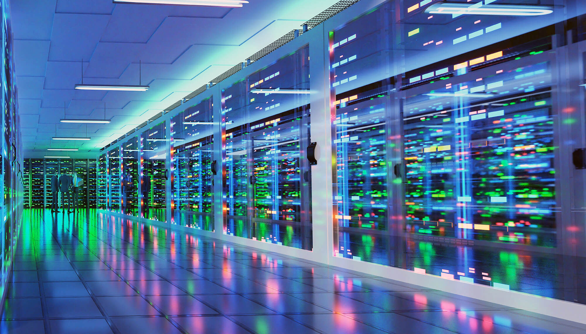 Three individuals in business attire at the end of a hallway in a server room of a data center