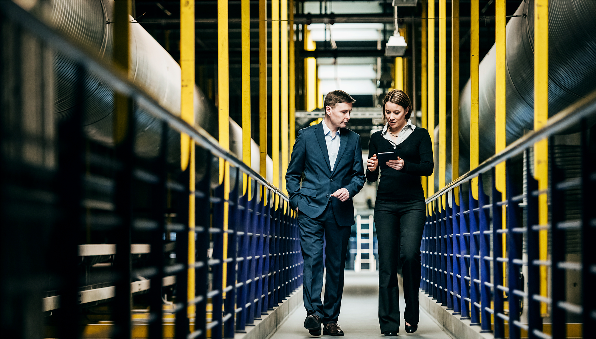 Two professionals talking while walking through a factory plant 