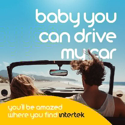 Two people riding in an open convertible on the beach